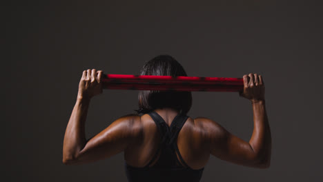 Rear-View-Studio-Shot-Of-Mature-Woman-Wearing-Gym-Fitness-Clothing-Exercising-With-Martial-Arts-Escrima-Sticks-2